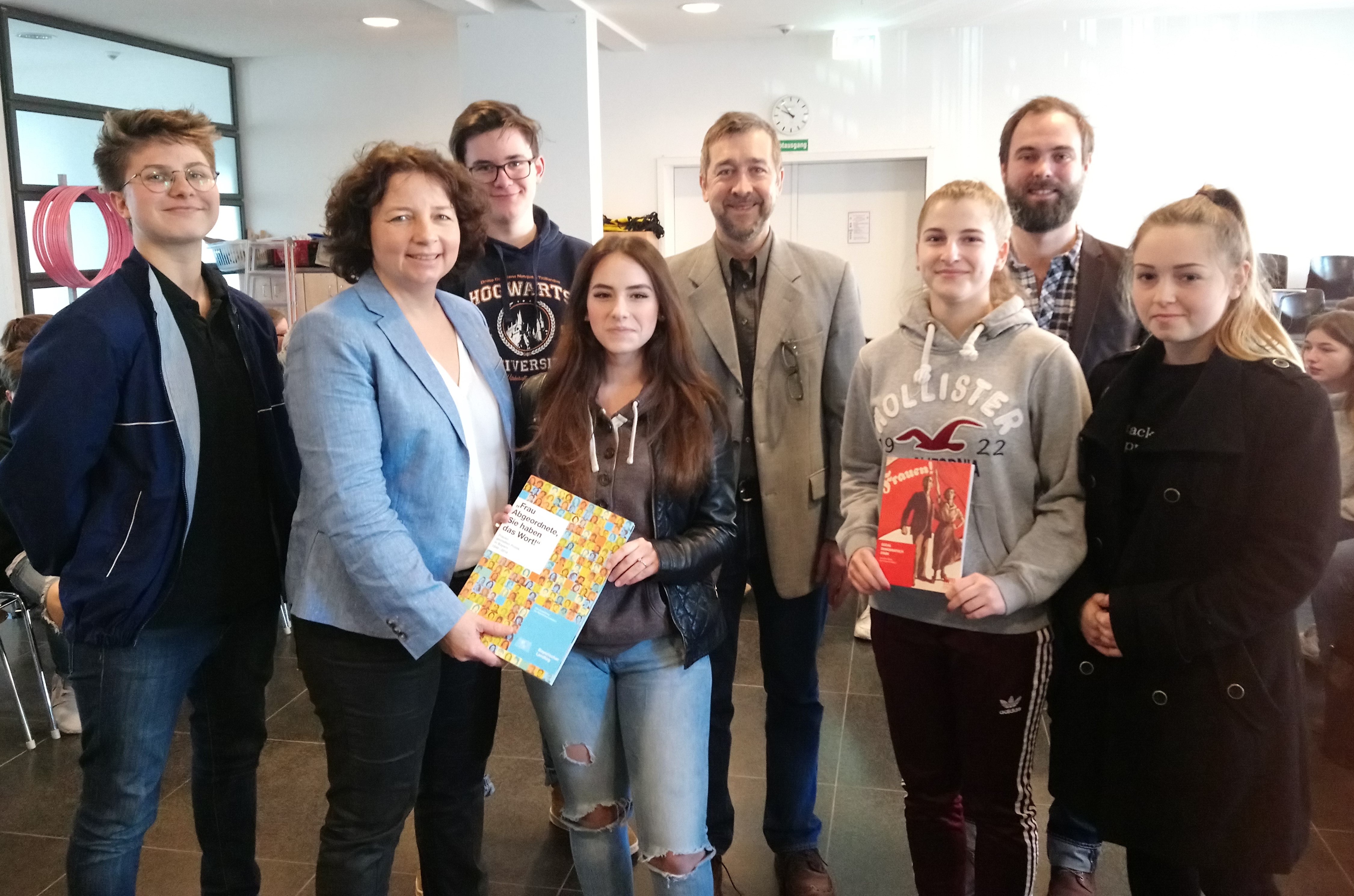 Frau Ruth Müller mit Schulleiter Herrn Dr. Oliver Klosa sowie der Lehrkraft Herr Markus Halander sowie mehrere Schülerinnen und Schüler